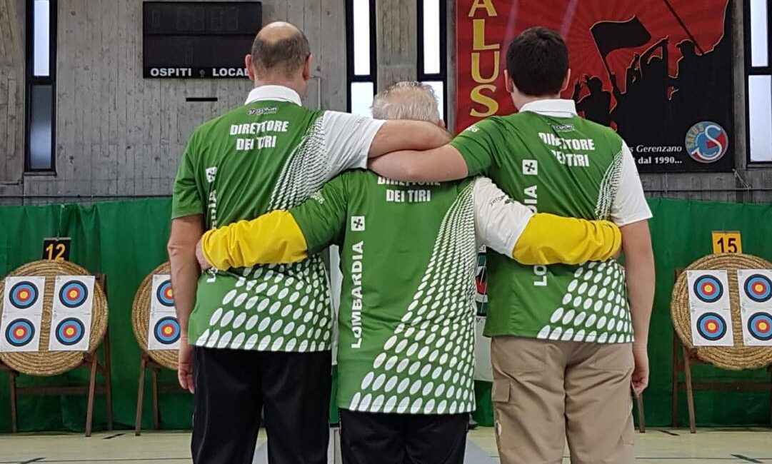 tre direttori dei tiri di spalle mostrano la maglietta del comitato FITARCO Lombardia
